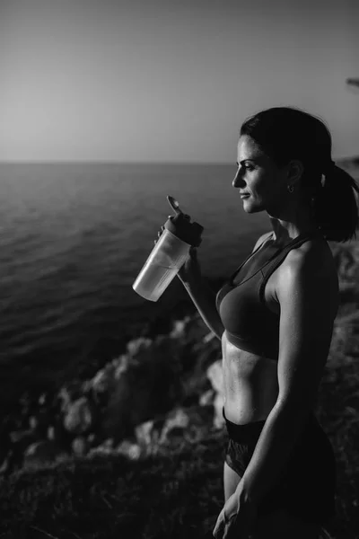 Beautiful girl with sports forms sports on the beach, drinking water, jumping, running, doing different exercises — Stock Photo, Image