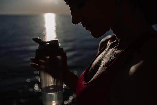 Hermosa chica con formas deportivas deportes en la playa, beber agua, saltar, correr, hacer diferentes ejercicios —  Fotos de Stock