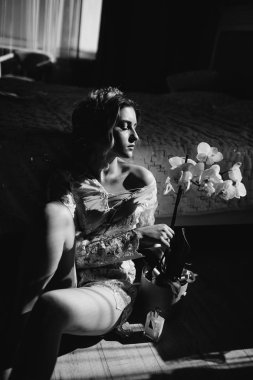 Güzel kadın iç çamaşırı uzun bacaklar seksi poz büyük pencereli, çiçek yatak üzerinde yatak eğilerek gösterilen. Cinsel anılar. Gelin boudoir. Düğün sabah.