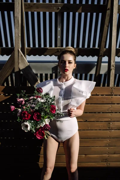 Schöne Frau Glamour hält einen Strauß in Händen trägt einen weißen Badeanzug — Stockfoto