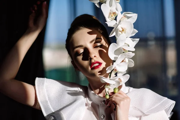 Menina loira bonita segurando orquídeas, luz solar dura, moda — Fotografia de Stock