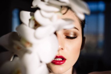 Güzel sarışın kız tutan orkide, sert güneş ışığı, moda