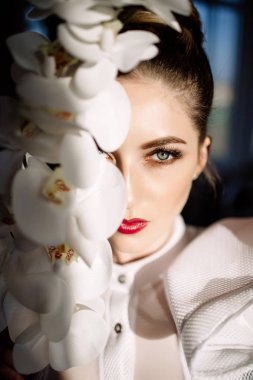 Güzel sarışın kız tutan orkide, sert güneş ışığı, moda
