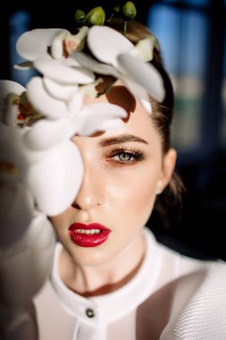 Güzel sarışın kız tutan orkide, sert güneş ışığı, moda