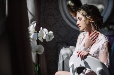 Gelinin sabah. Güzel Sanatlar düğün. Beyaz dantel boudoir dalgalı sarı saçlı genç bir gelin ve tepeden bakıyorum utanarak poz onun elinde bir buket portre