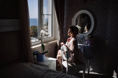 Gelinin sabah. Güzel Sanatlar düğün. Beyaz dantel boudoir dalgalı sarı saçlı genç bir gelin ve tepeden bakıyorum utanarak poz onun elinde bir buket portre