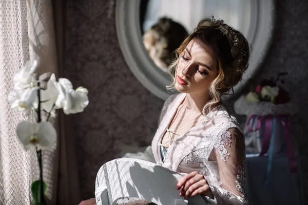 Gelinin sabah. Güzel Sanatlar düğün. Beyaz dantel boudoir dalgalı sarı saçlı genç bir gelin ve tepeden bakıyorum utanarak poz onun elinde bir buket portre