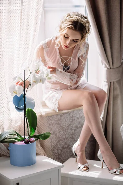 Belle fille arrosant une orchidée de fleur avec arrosoir pour des fleurs — Photo