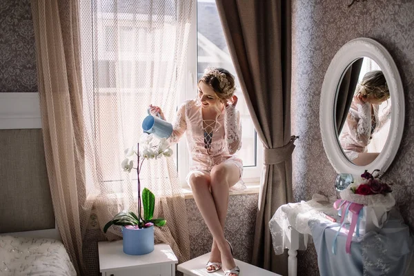 Beautiful girl watering a flower orchid with watering can for flowers — Stock Photo, Image