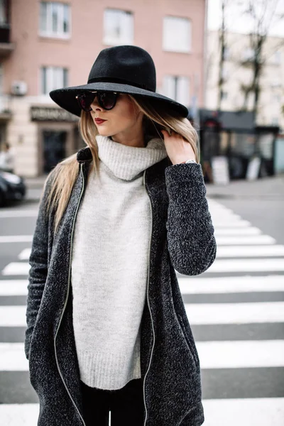 Retrato de cerca de una joven hermosa mujer de moda con gafas de sol. Un modelo en un elegante sombrero de ala ancha en un cruce peatonal — Foto de Stock