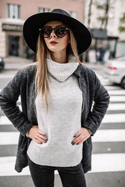 Retrato de cerca de una joven hermosa mujer de moda con gafas de sol. Un modelo en un elegante sombrero de ala ancha en un cruce peatonal — Foto de Stock