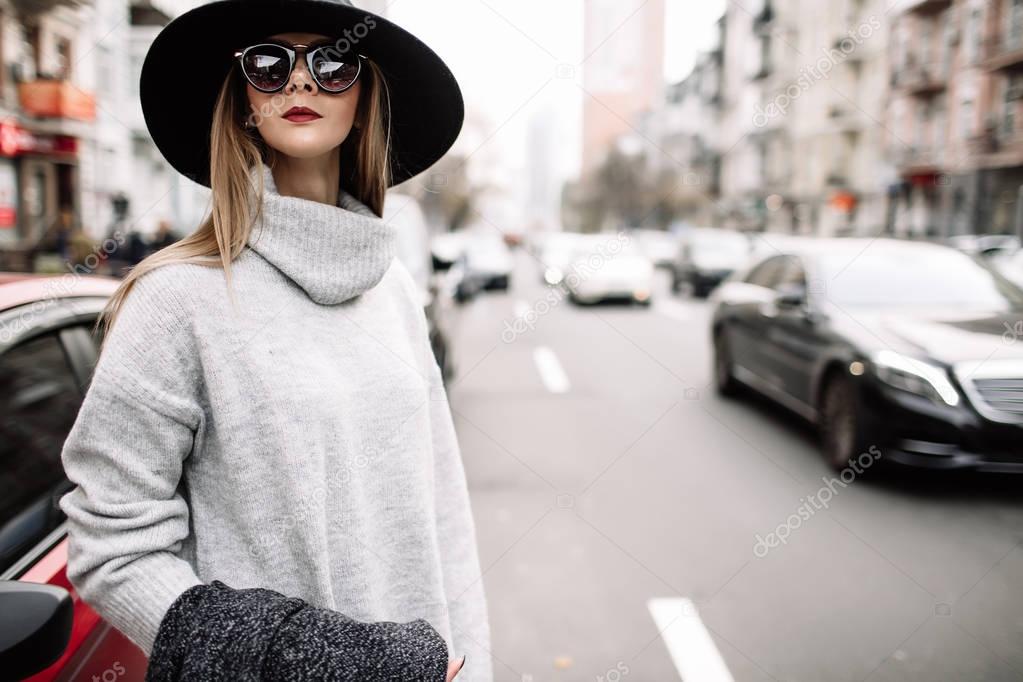 Closeup portrait of a young beautiful fashionable woman wearing sunglasses. A model in a stylish wide-brimmed hat
