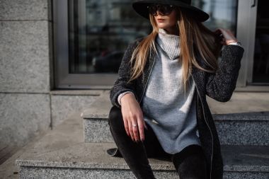Portre portre genç bir güzel moda kadın güneş gözlüğü takıyor. Manken şapkalı bir şık geniş ekledi. Gri tonları uyum benzer giysilerle. Çekim Uleach tarzı. Kadın moda