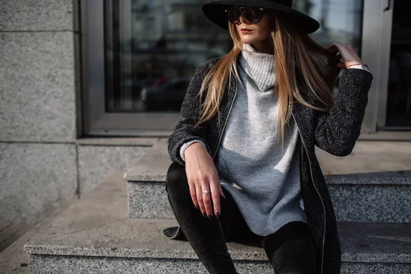 Retrato de cerca de una joven hermosa mujer de moda con gafas de sol. Un modelo con un elegante sombrero de ala ancha. Ropa armoniosamente similar en tonos grises. Estilo de disparo de lixiviación. Moda femenina — Foto de Stock