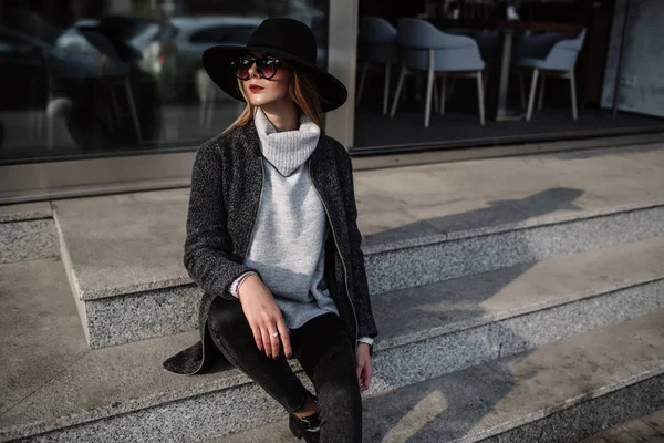 Portrait d'une jeune fille à la mode portant des lunettes de soleil. Modèle dans un chapeau noir élégant. Vêtements harmonieusement similaires dans des tons gris. Street style. Mode féminine . — Photo