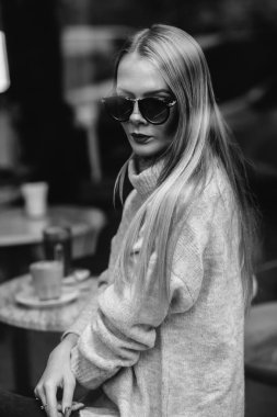 Kız bir kafede bir masada kahve, içecekler çay, görünüm pencere camı delip, moda vurdu