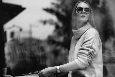 Kız bir kafede bir masada kahve, içecekler çay, görünüm pencere camı delip, moda vurdu