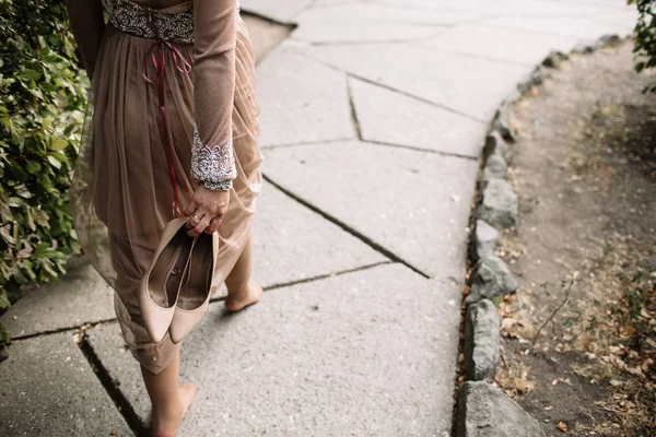 Mariée tient les chaussures de mariage dans ses mains . — Photo