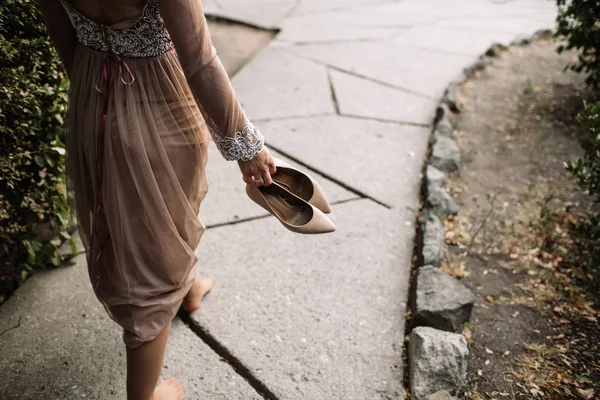 Noiva segura os sapatos de casamento em suas mãos . — Fotografia de Stock
