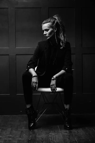 Sexy joven modelo en ropa oscura, sentado en una silla blanca y p — Foto de Stock