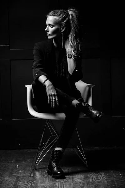 Σέξι νεαρό μοντέλο σε σκούρα ρούχα, κάθεται σε μια καρέκλα λευκή και p — Φωτογραφία Αρχείου
