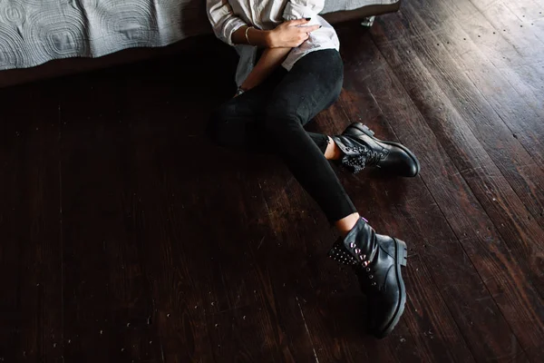 Detail z černé boty na nohách dívku sedící na gauči — Stock fotografie