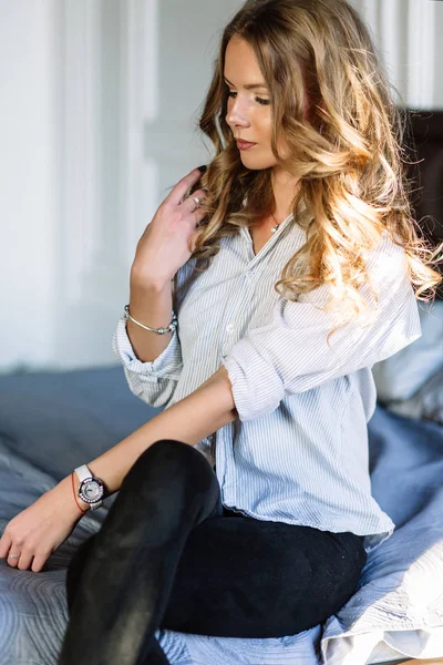 En flicka med långt blont hår klädd i svarta jeans, en randig sh — Stockfoto