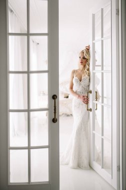 Düğün. Kapalı beyaz bir stüdyoda, güzel bir elbise içinde gelin evde severim. Şık düğün tarzı tam uzunlukta alınır. Bir gelin gibi kıvırcık saçlı genç çekici sarışın model