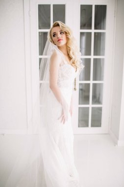 Düğün. Kapalı beyaz bir stüdyoda, güzel bir elbise içinde gelin evde severim. Şık düğün tarzı tam uzunlukta alınır. Bir gelin gibi kıvırcık saçlı genç çekici sarışın model