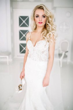 Düğün. Kapalı beyaz bir stüdyoda, güzel bir elbise içinde gelin evde severim. Şık düğün tarzı tam uzunlukta alınır. Bir gelin gibi kıvırcık saçlı genç çekici sarışın model