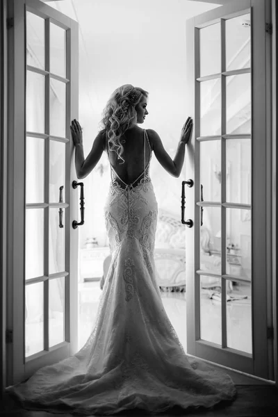 Wedding. Bride in a beautiful dress indoors in a white studio, like at home. The fashionable wedding style is taken in full length. Young attractive blond model with curly hair, like a bride — Stock Photo, Image