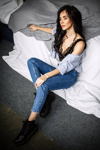 Cute młoda kobieta siedzi na podłodze w dżinsach i niebieską koszulę, moda — Zdjęcie stockowe