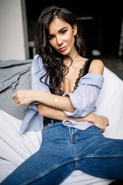 Giovane donna carina seduta sul pavimento in jeans blu e camicia blu, moda — Foto Stock