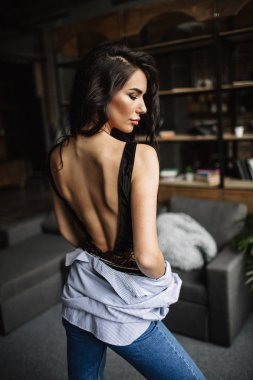 Ön plan. Güzel esmer bir kitaplık ve Li, moda stil arka arka planda bir odada mavi tişört ve kot pantolon giymiş