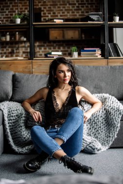 Mavi jeans ve mavi gömlek, moda katta oturan sevimli genç kadın