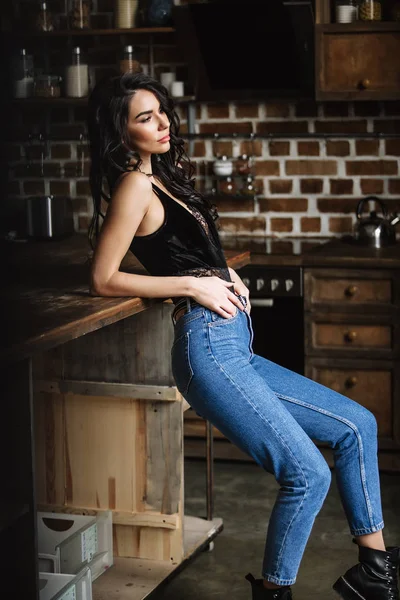 Schöne Brünette in der Küche, moderne Hausfrau, Mode, hölzerne braune Möbel, bekleidet mit blauer Jeans und blauem Hemd — Stockfoto