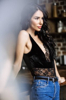 Güzel esmer kahverengi ahşap mobilya, mutfak, modern ev hanımı, moda mavi kot pantolon ve mavi bir gömlek giymiş