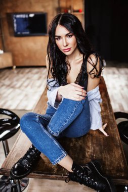 Güzel esmer kahverengi ahşap mobilya, mutfak, modern ev hanımı, moda mavi kot pantolon ve mavi bir gömlek giymiş