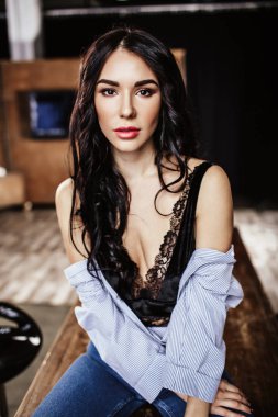 Güzel esmer kahverengi ahşap mobilya, mutfak, modern ev hanımı, moda mavi kot pantolon ve mavi bir gömlek giymiş