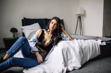 Mavi jeans ve mavi gömlek, moda katta oturan sevimli genç kadın