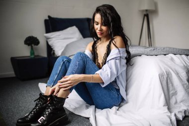 Mavi jeans ve mavi gömlek, moda katta oturan sevimli genç kadın