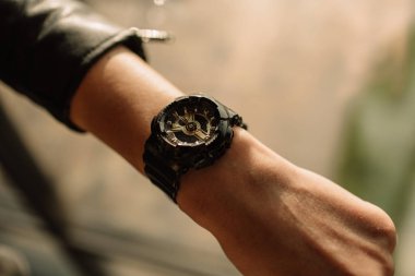 Bir kadının elinde altın oklar olan siyah saat. Moda saatleri modern tarzdadır.