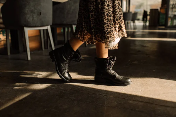 Dívka v leopardí sukni a černé boty v tvrdém světle na betonové podlaze. Klávesa na botách — Stock fotografie