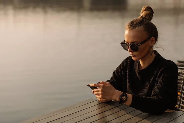 Young businesswoman working. Works on the phone, holds the phone in his hands, against the backdrop of a yacht, water.