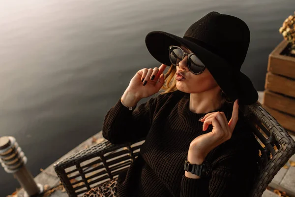 Une jeune femme d'affaires qui travaille. Elle porte un chapeau noir et des lunettes de soleil sur la tête. fond du yacht, l'eau — Photo