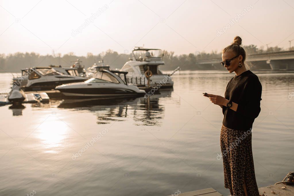 Young businesswoman working. Works on the phone, holds the phone in his hands, against the backdrop of a yacht, water.