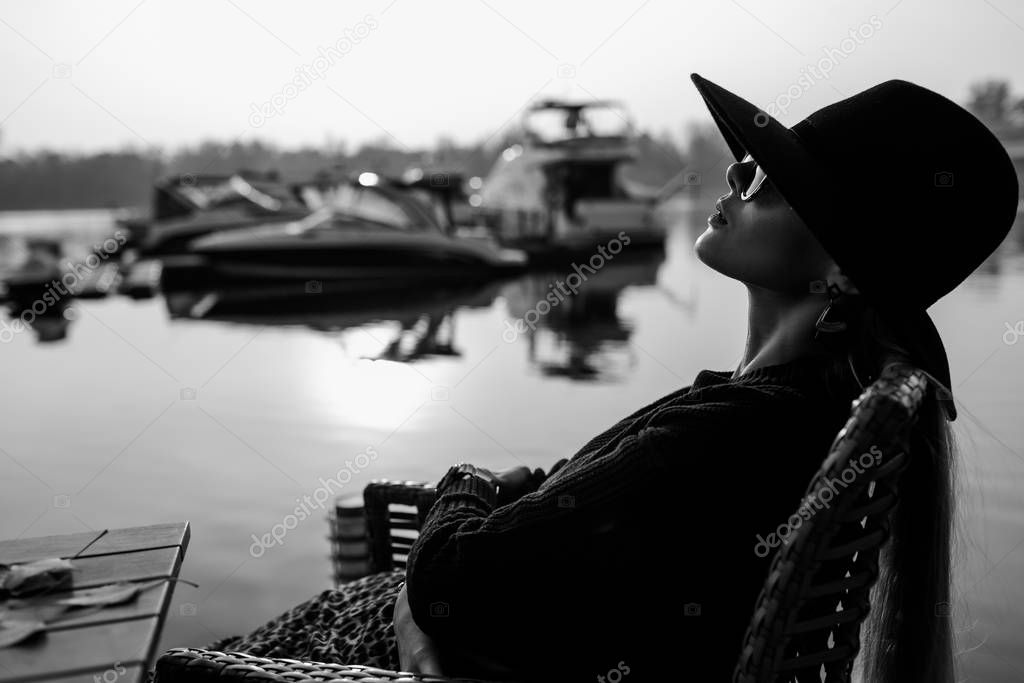 Young businesswoman working. She wears a black hat and sunglasses on her head. background of the yacht, water