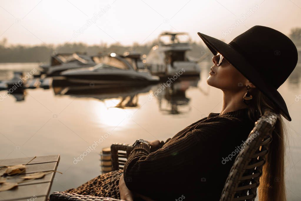 Young businesswoman working. She wears a black hat and sunglasses on her head. background of the yacht, water