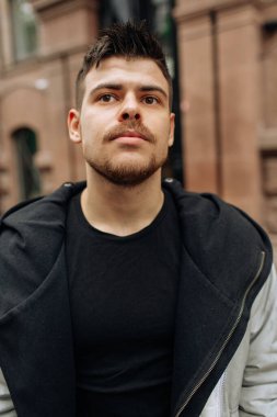 Şehirde dolaşan genç bir adamın portresi. Esmer, sakallı. Neşeli, güzel gülümseme.