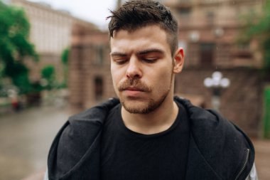 Şehirde dolaşan genç bir adamın portresi. Esmer, sakallı. Neşeli, güzel gülümseme.